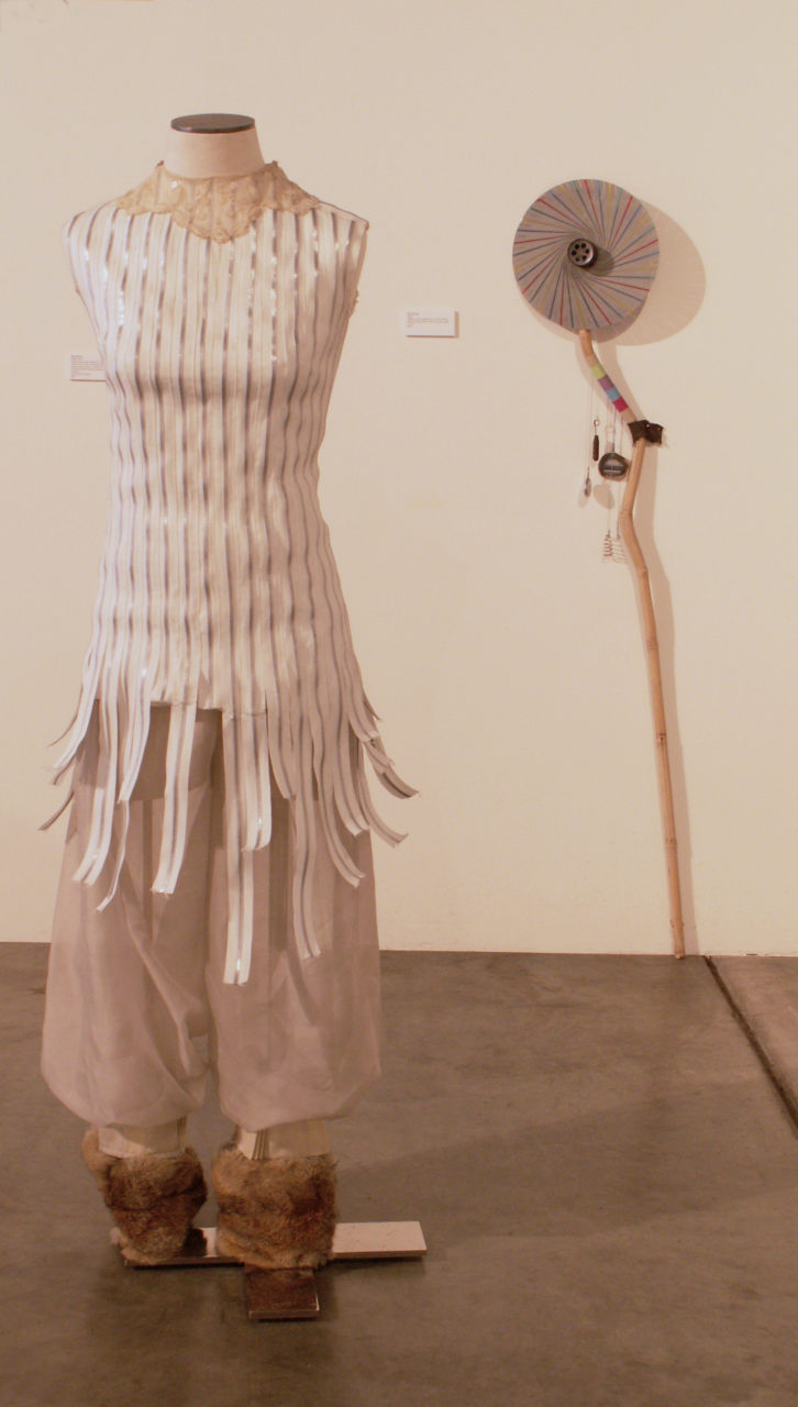 Rabbit Dress- roll of aluminum zipper, vintage lace collar, vinyl boots, chain, earring. Puff Pants- sheer drapery, fur (rabbit) from leather moccasin boots, trim of pinch pleating from sheer drapery, Size Small / Medium. Staff-bamboo stick, plastic disc, metal sanding drum, string, pocket watch, springs, agate, 6x57”